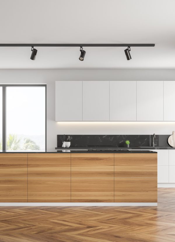 Interior of kitchen with white walls, wooden floor, white countertops and cupboards, wooden island with built in cooker and two ovens in the wall. 3d rendering